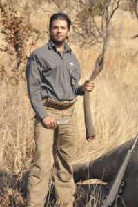 Donald Trump, Jr. holding an elephant's tail.